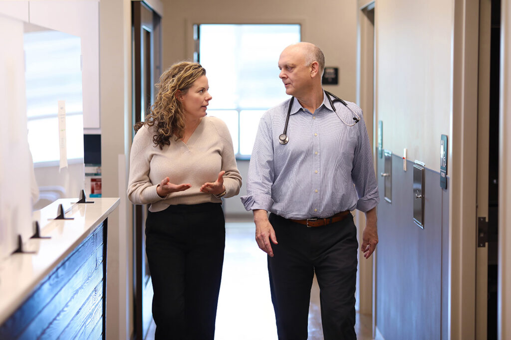Doctor and healthcare professional walking and discussing patient care inside a modern primary care clinic