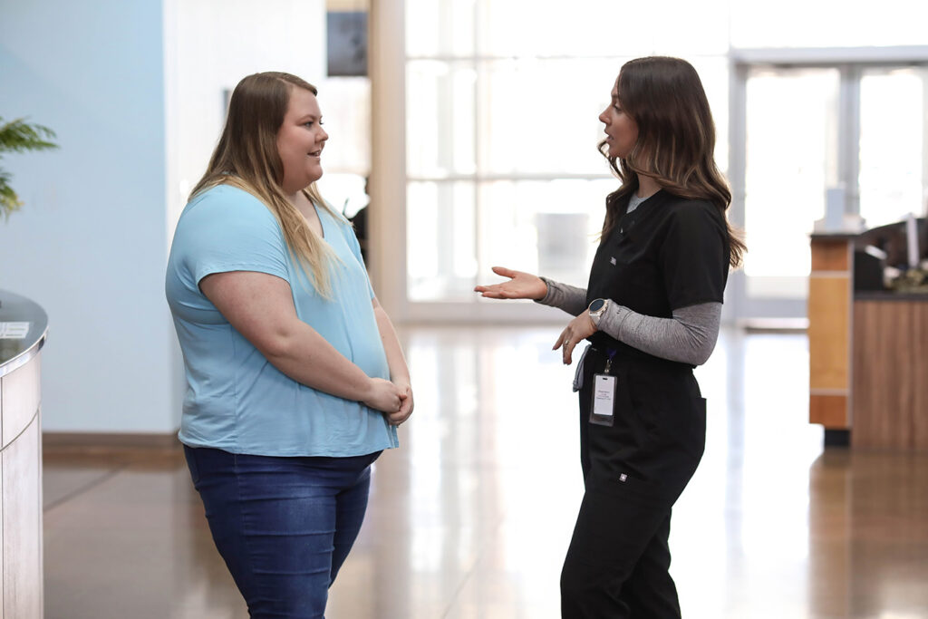 Nurse in conversation with patient in bright clinic lobby, highlighting approachable, relationship-based primary care