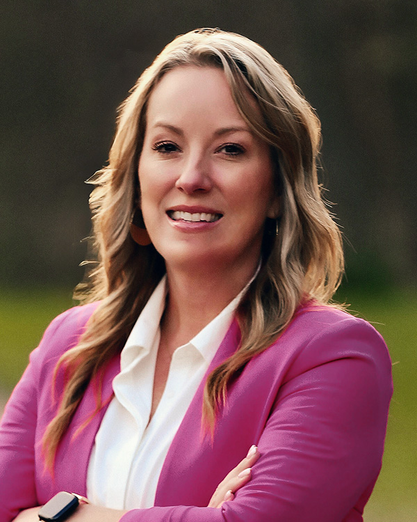 Portrait of Ashley Berry, Chief Clinical Operations Officer at One to One Health, standing outdoors in a bright pink blazer
