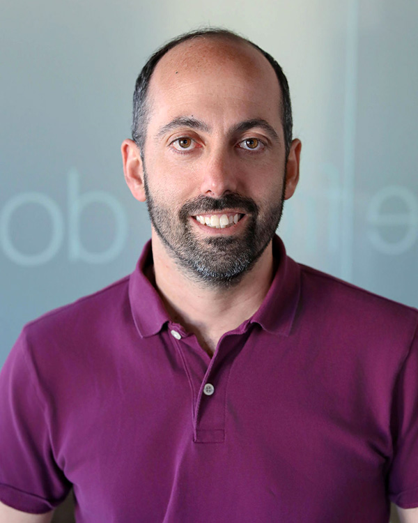 Portrait of Jesse Rosenthal, Vice President of Virtual Operations at One to One Health, wearing a maroon polo shirt in a modern office setting